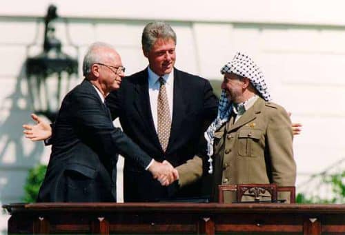 יצחק רבין ויאסר ערפאת לוחצים יד מול ביל קלינטון בחתימת הסכם אוסלו