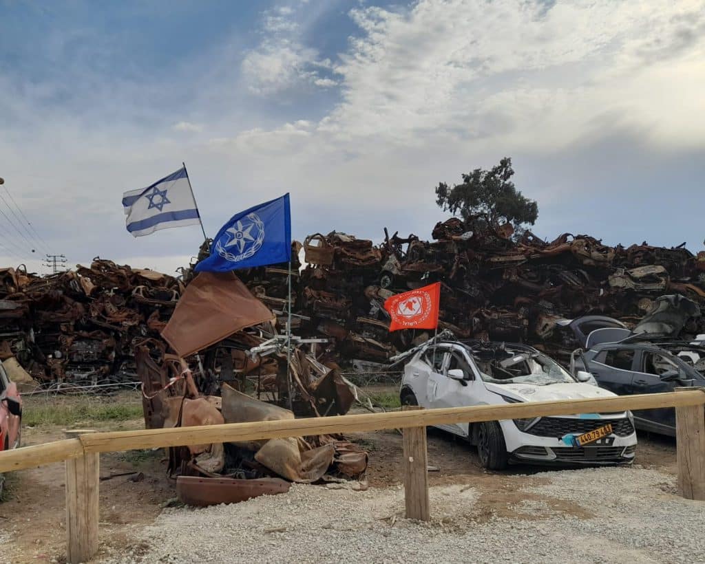 אנדרטת הרכבים עם רכבים שרופים ודגלי ישראל, המשטרה ומכבי האש