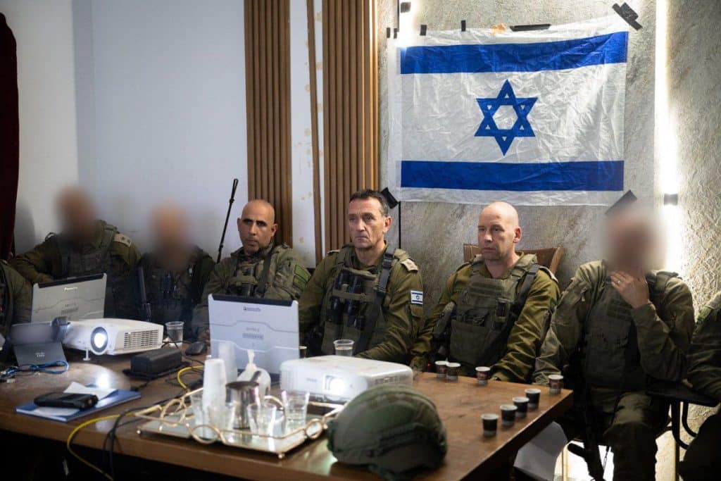 Lieutenant Hertzi Halevi and staff near desk and Israeli flag behind
