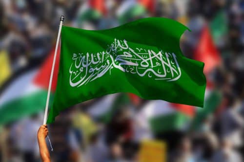 יד מניפה את דגל חמאס וברקע המון עם דגלי פלסטין