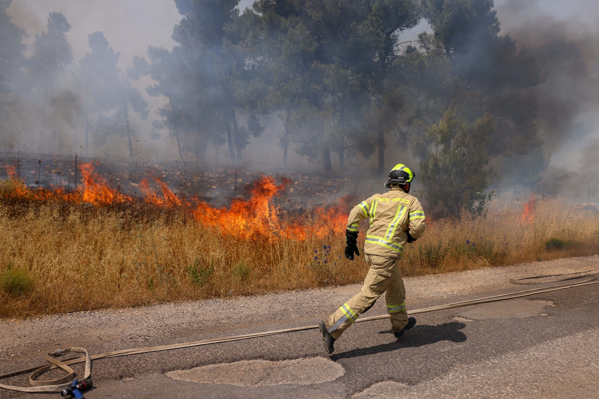 Firefighters work to extinguish a fire sparked by rockets launched from Lebanon, at the Biriya Forest in northern Israel, June 13, 2024