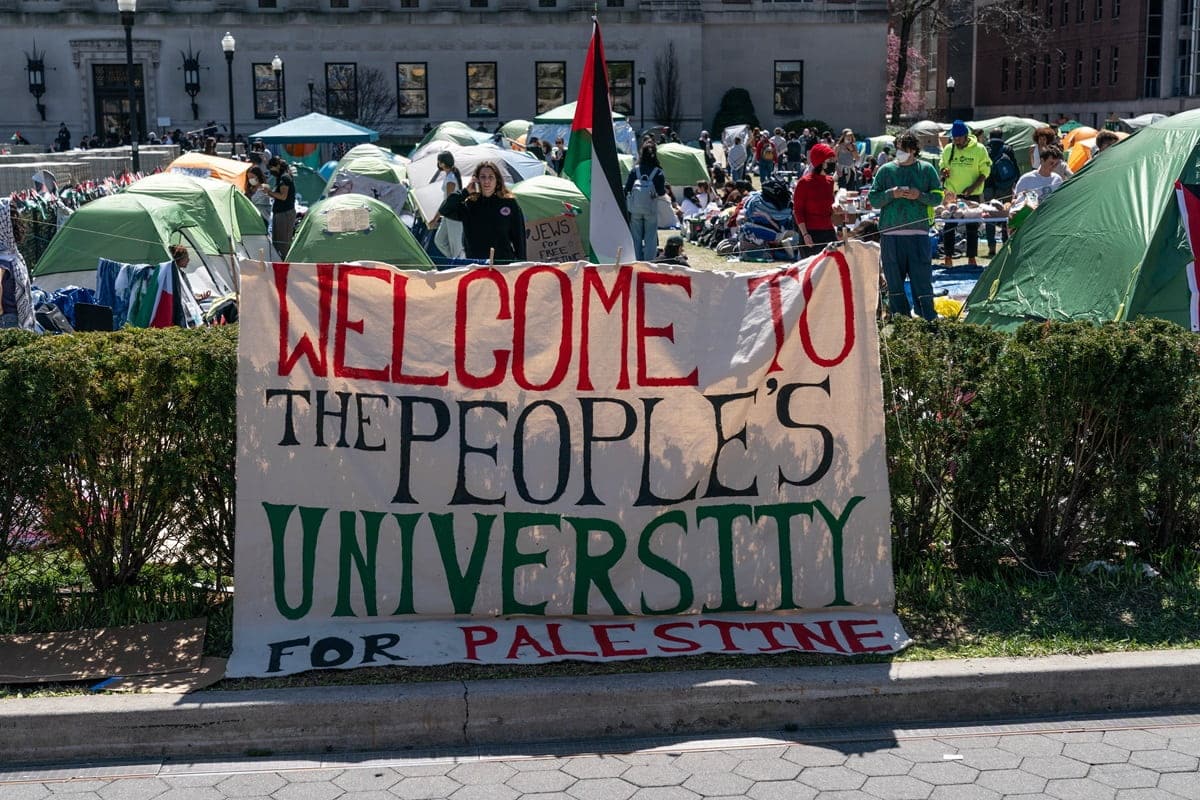 'Welcome to the people's university for Palesine' sign, demonstrators tents and palestinian flags in the background