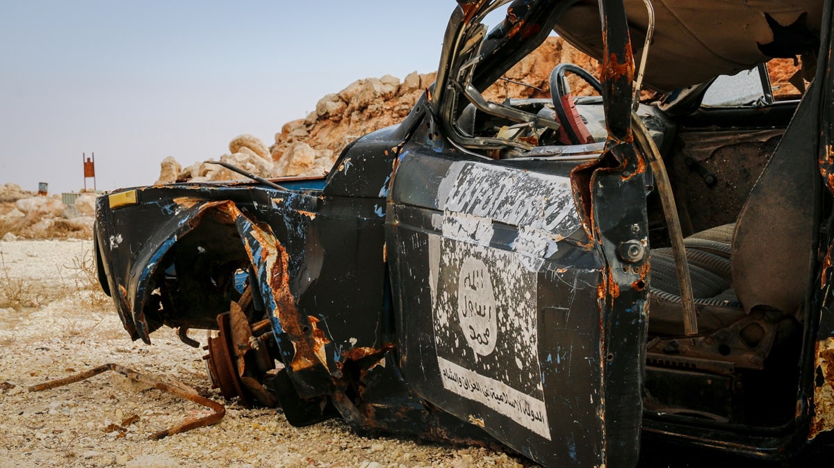 burnt car with arabic writing in desert