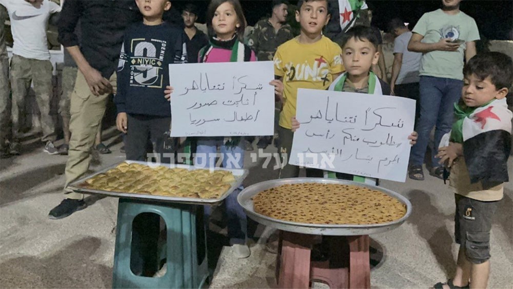 children with syrian flags, signs and plates with baklava