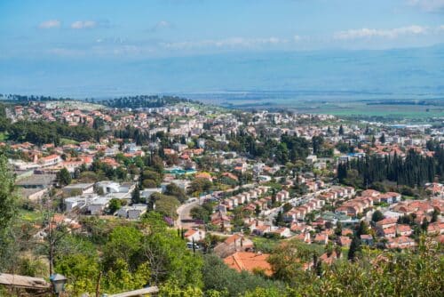 ראש פינה עם גגות אדומים בצפון הארץ ועמק החולה והחרמון בקו אופק.