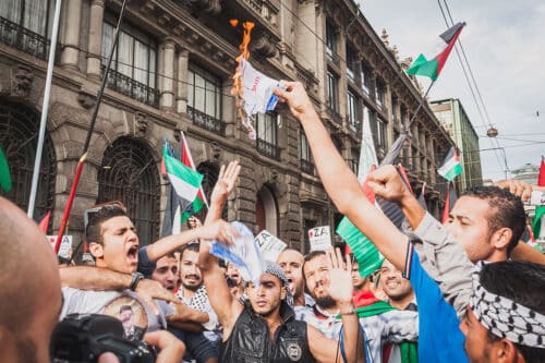 demonstrators with palestinian flags burning israeli flag