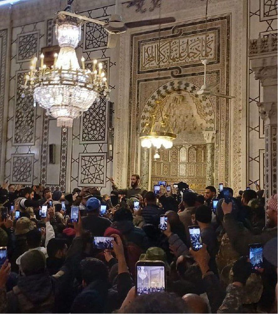 Al Julani speaking to large crowd in a decorated mosque