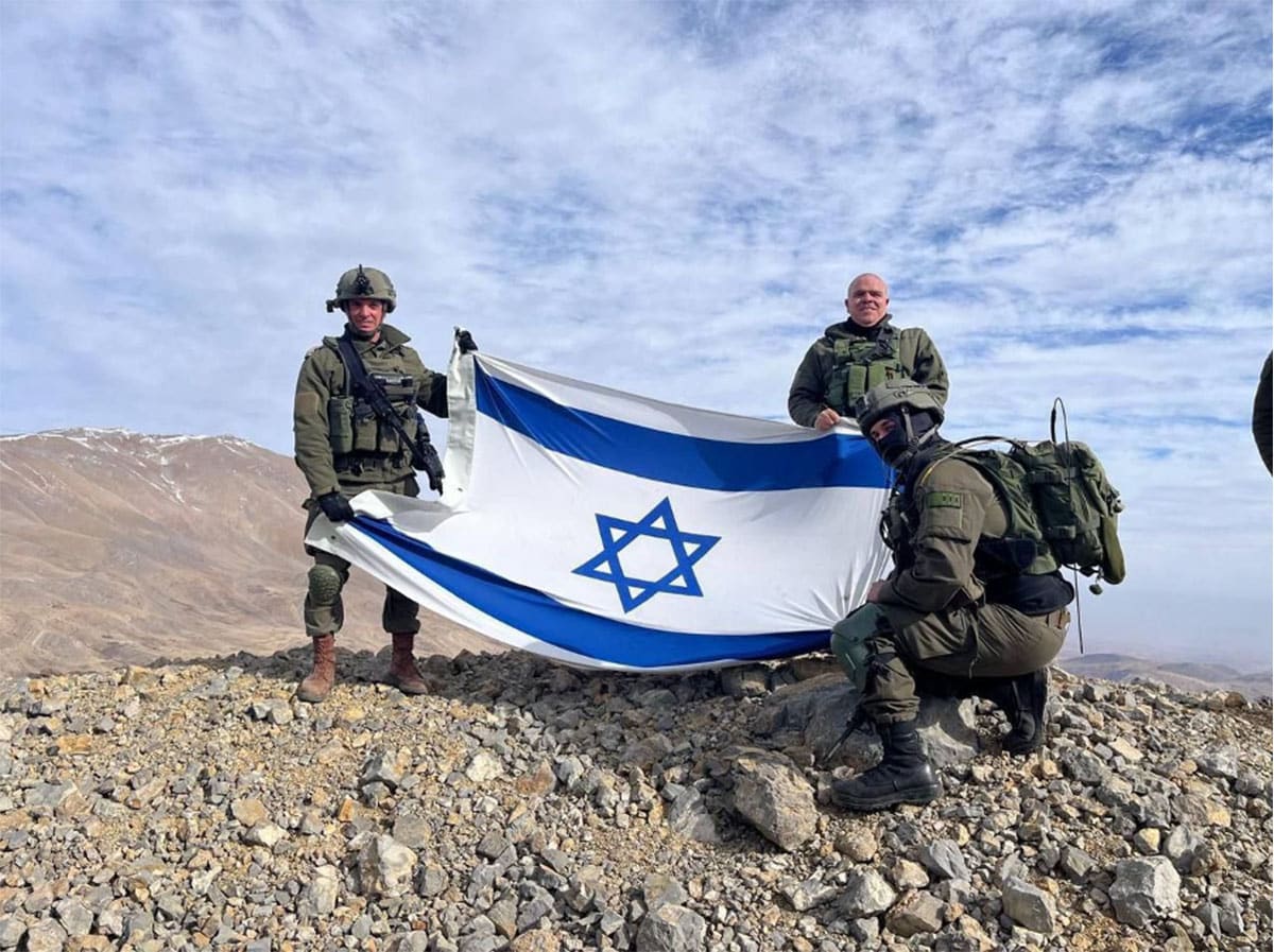 soldiers holding Israeli flag on mountain top