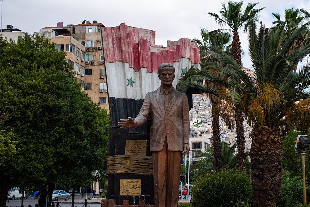 Hafez el Assad statue with syrian flag