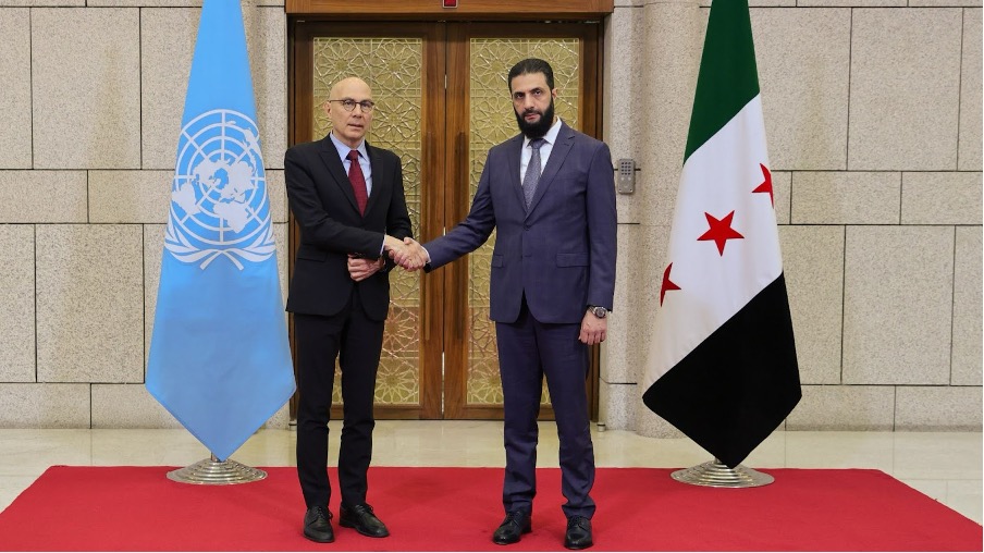 Al-Sharaa shaking hands with UN representative